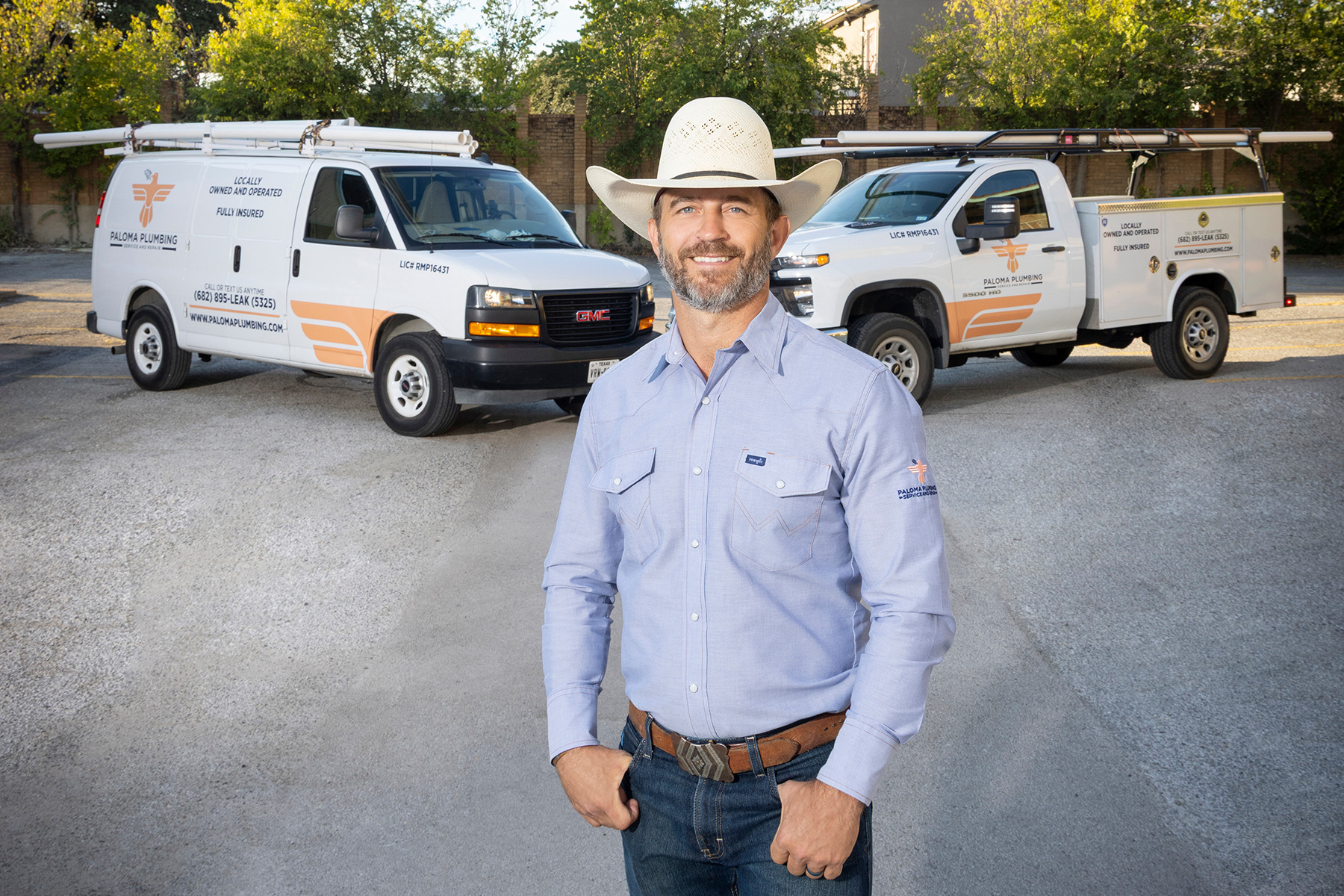 Clayton Warren in front of two branded Paloma Plumbing service trucks